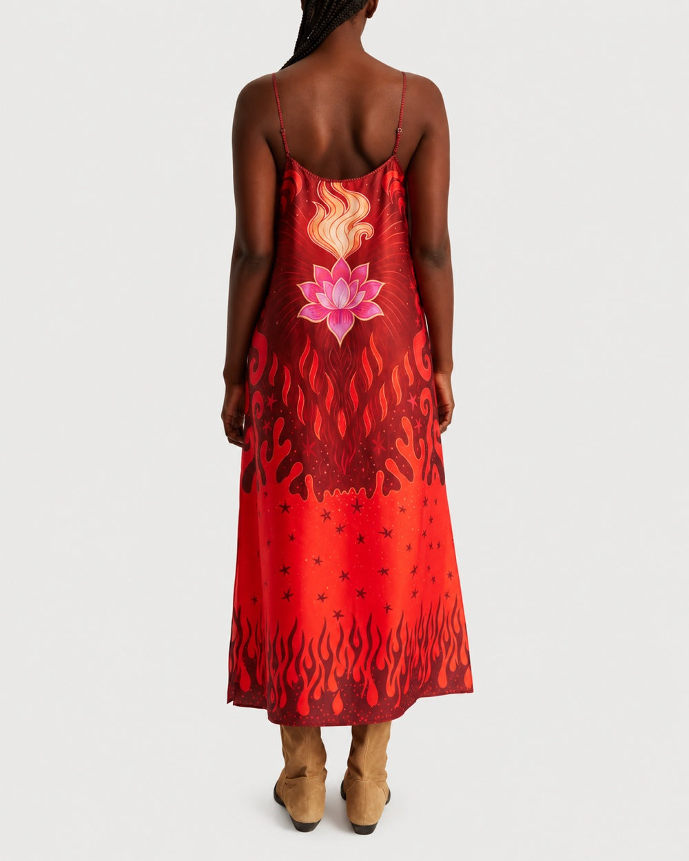 A person wears a bias-cut ME369 Olivia Camisole Dress Red Aura in a red print featuring a lotus flower graphic above flames and stars.