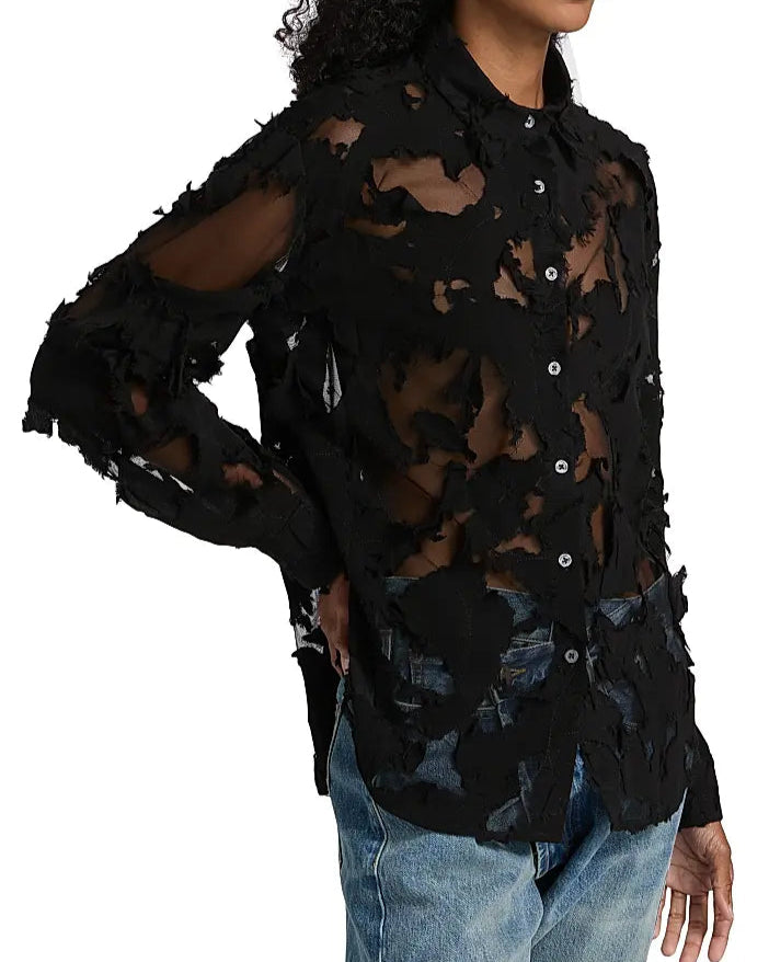 A person wears the R13 Slim Abstract Print Shirt—a black sheer long-sleeve with frayed patches, collar, and distressed details that reveal skin—paired with blue jeans.
