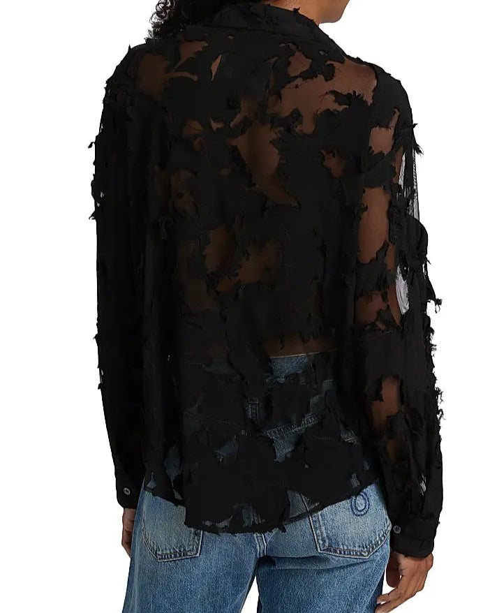 Someone wearing the R13 Slim Abstract Print Shirt, a sheer black distressed long-sleeve top with holes and frayed details, paired with blue jeans and shown from the back.