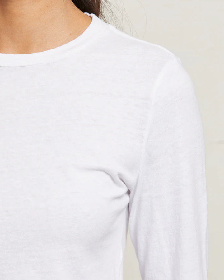 Close-up of a person wearing a white long-sleeve shirt against a neutral background