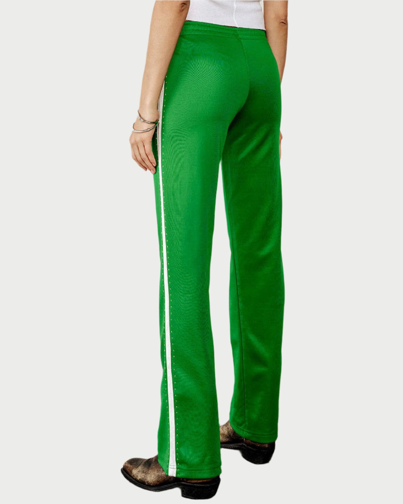 A person wearing RE/DONE Sunland Track Pant in bright green with a white side stripe, paired with a white top, bracelets, and black shoes, stands facing away from the camera against a plain background for a sporty Western-inspired look.