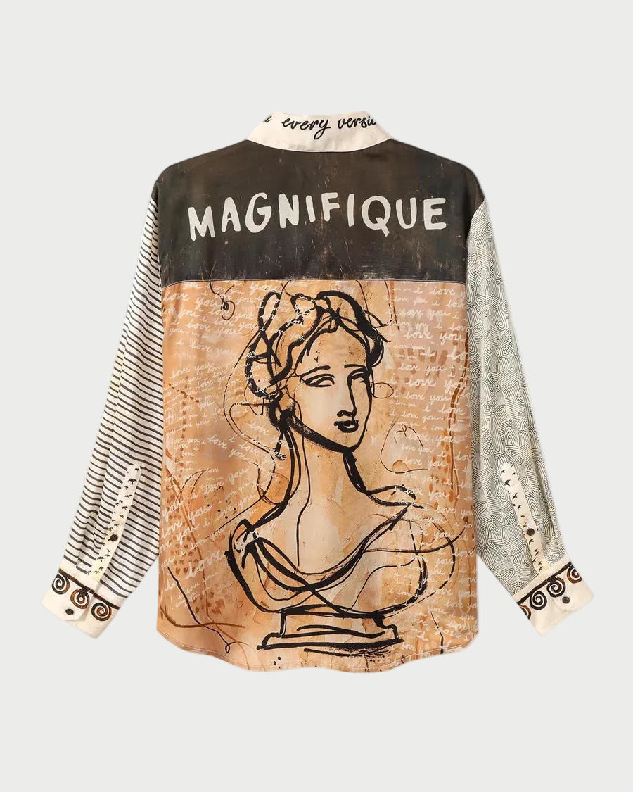 A long-sleeve button-up shirt with a complex graphic print. The back features a dark brown top section with the word 'MAGNIFIQUE' in white, a central beige panel with a black line art bust illustration, and patterned cream and gray sleeves.