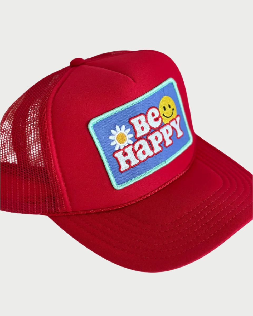 The LOCAL BEACH Be Happy Trucker Hat in red features a vibrant embroidered patch with "Be Happy," a sunflower, and a yellow smiley face on a blue background, embodying beach vibes.