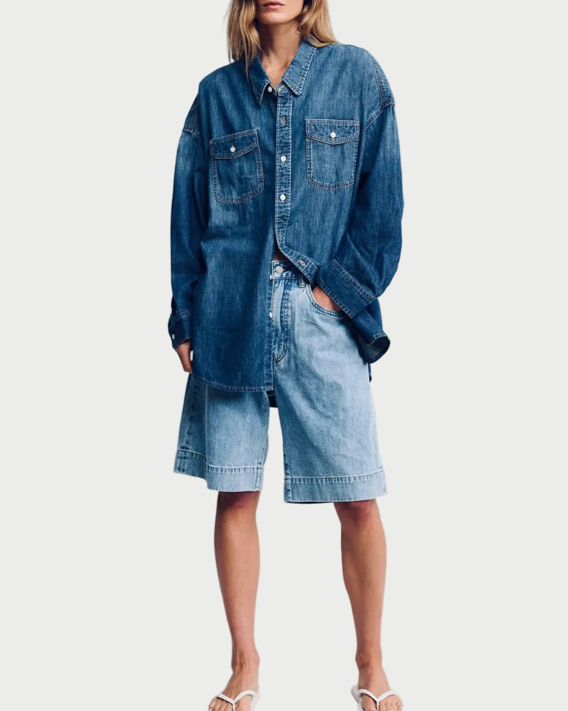 Person wearing a denim jacket and shorts on a plain background