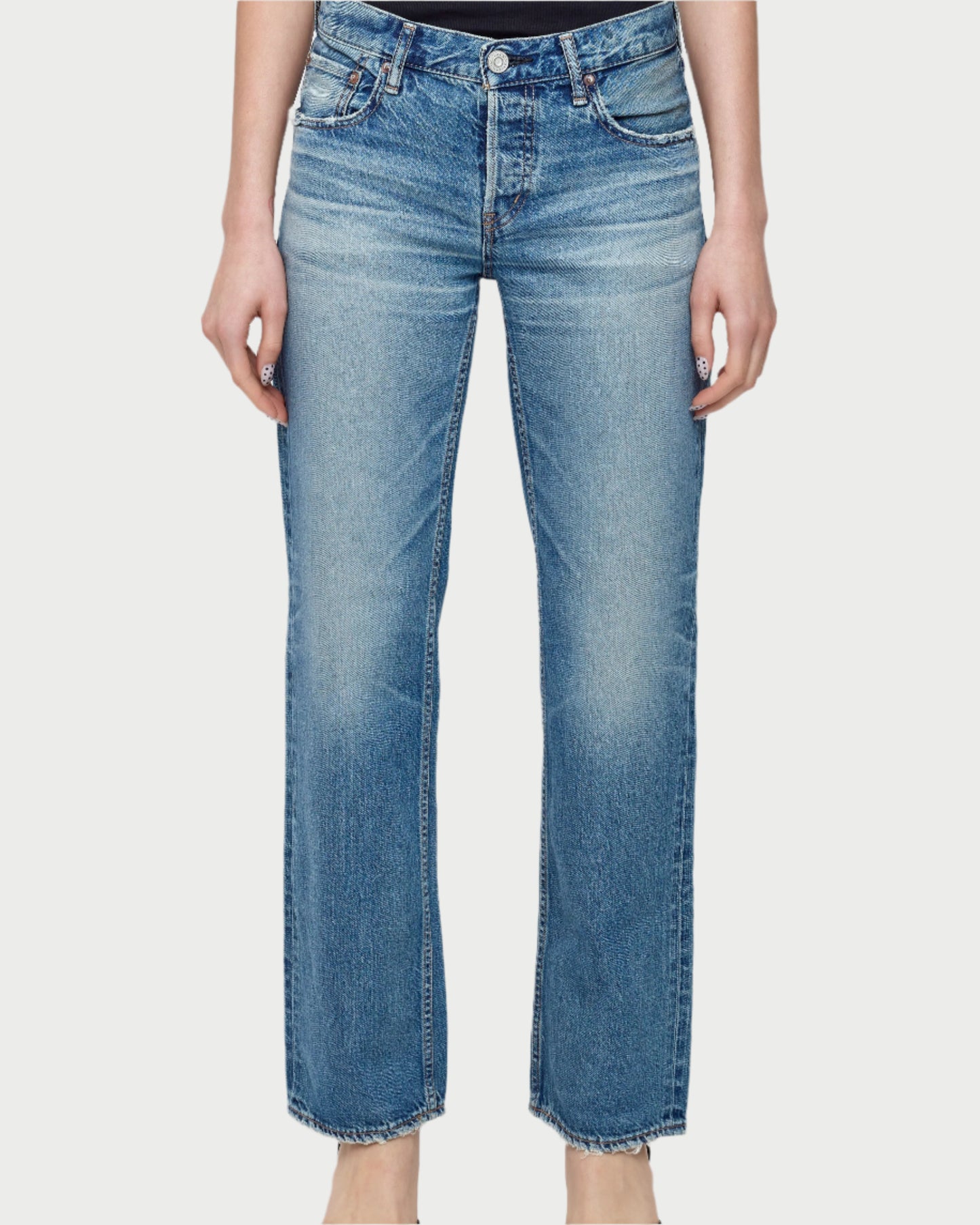 A person wears Moussy’s Millsboro Straight Low Jeans in light blue Japanese cotton denim with a straight leg, faded wash, and classic five-pocket design, standing barefoot against a white background.