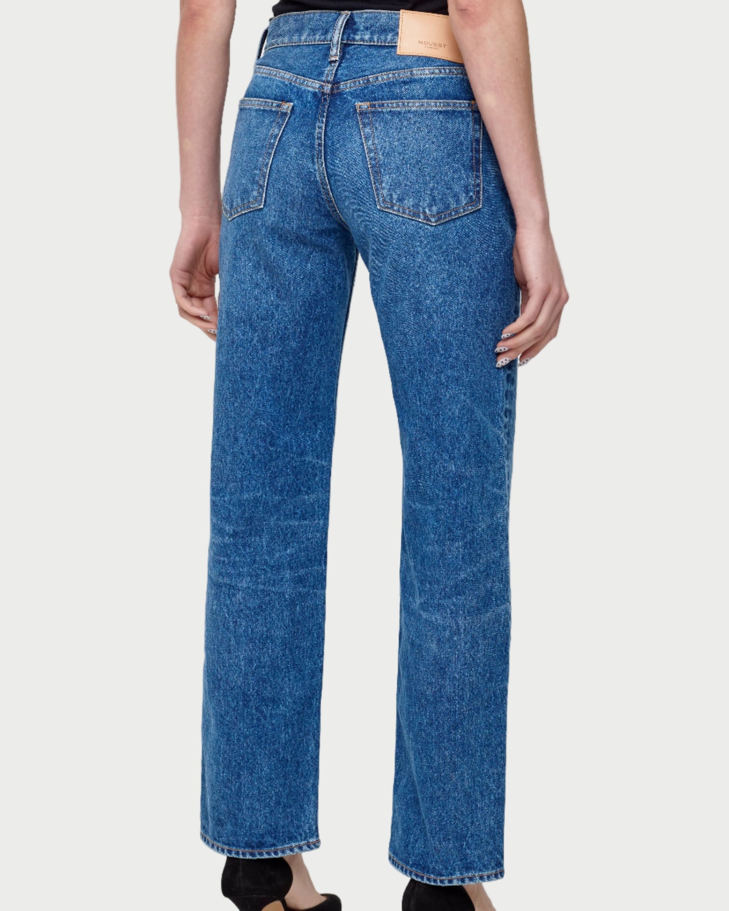 Person wearing blue jeans on a plain background