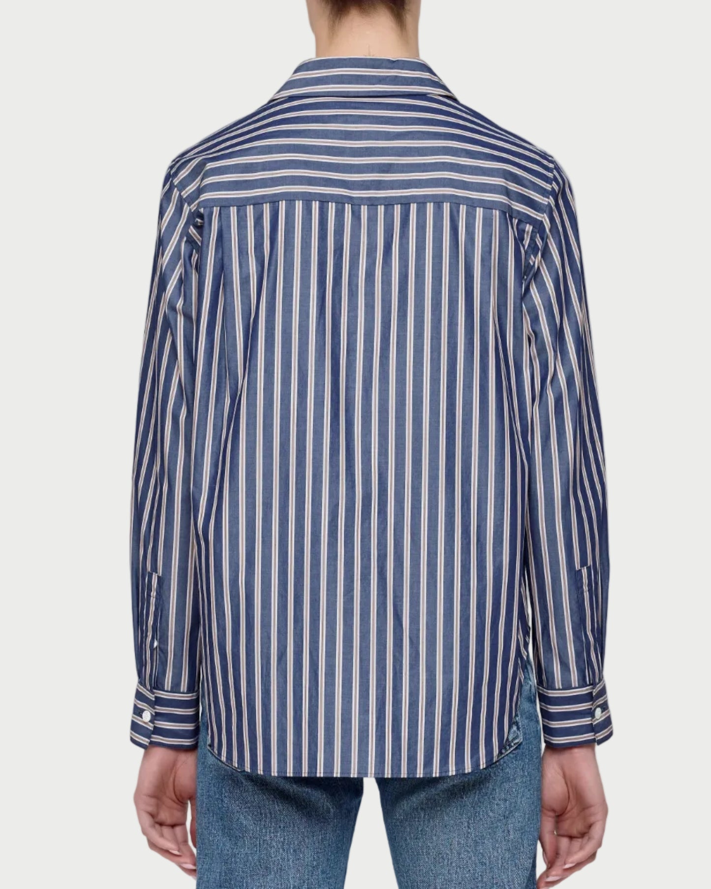 Person wearing a blue and white striped shirt and jeans on a plain background