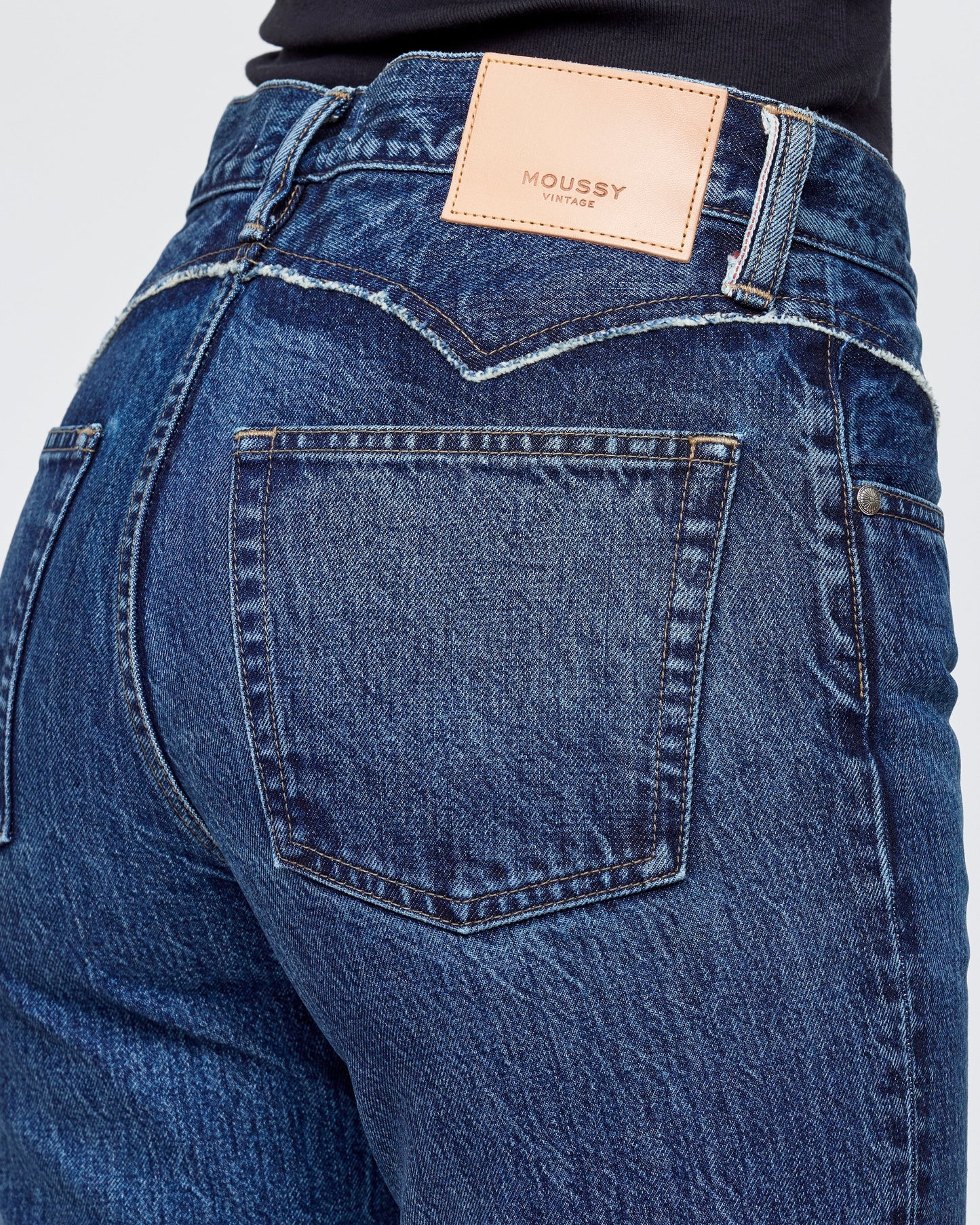 Close-up of blue jeans with a brand label on a white background