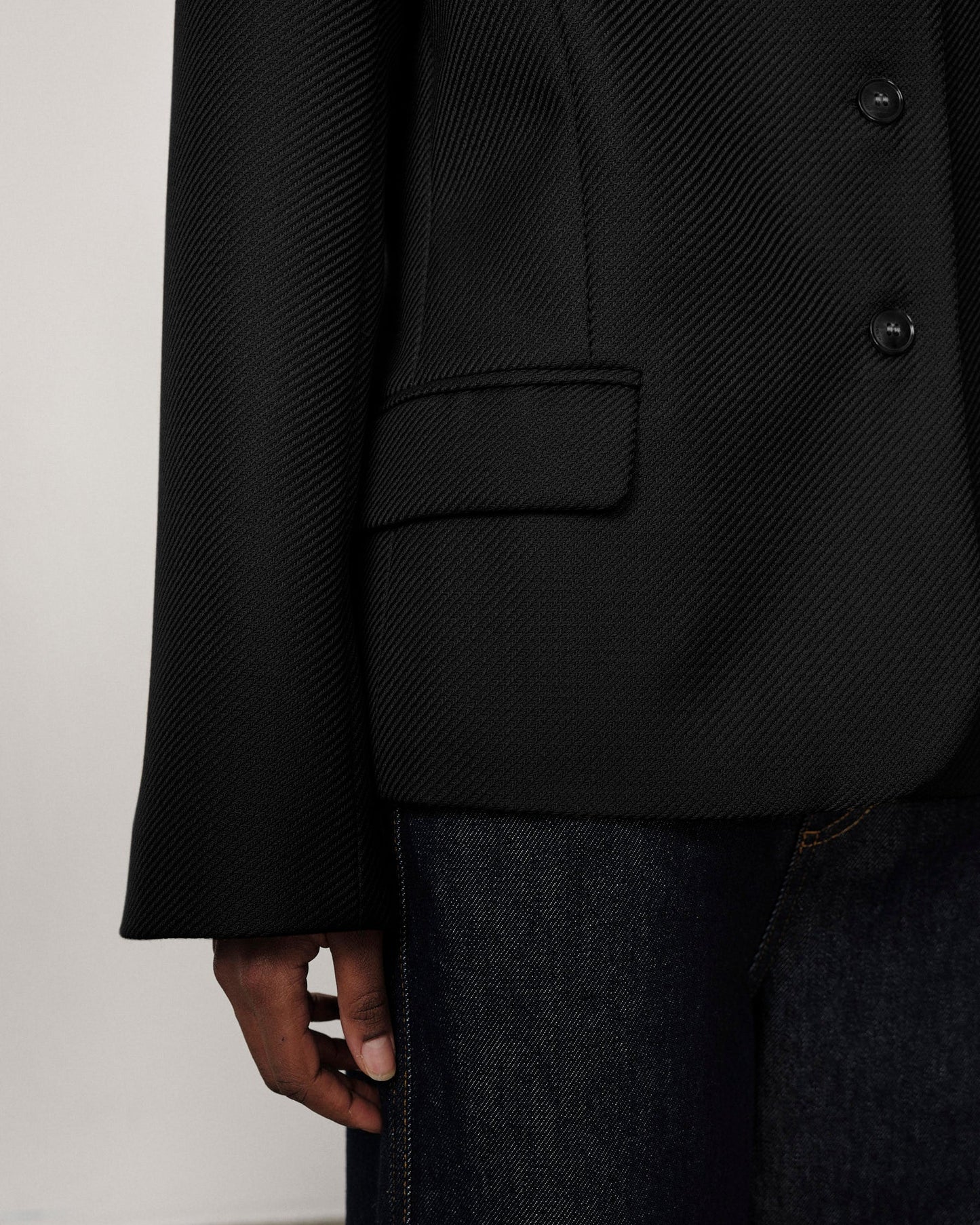 Person wearing a black textured coat with a plain background