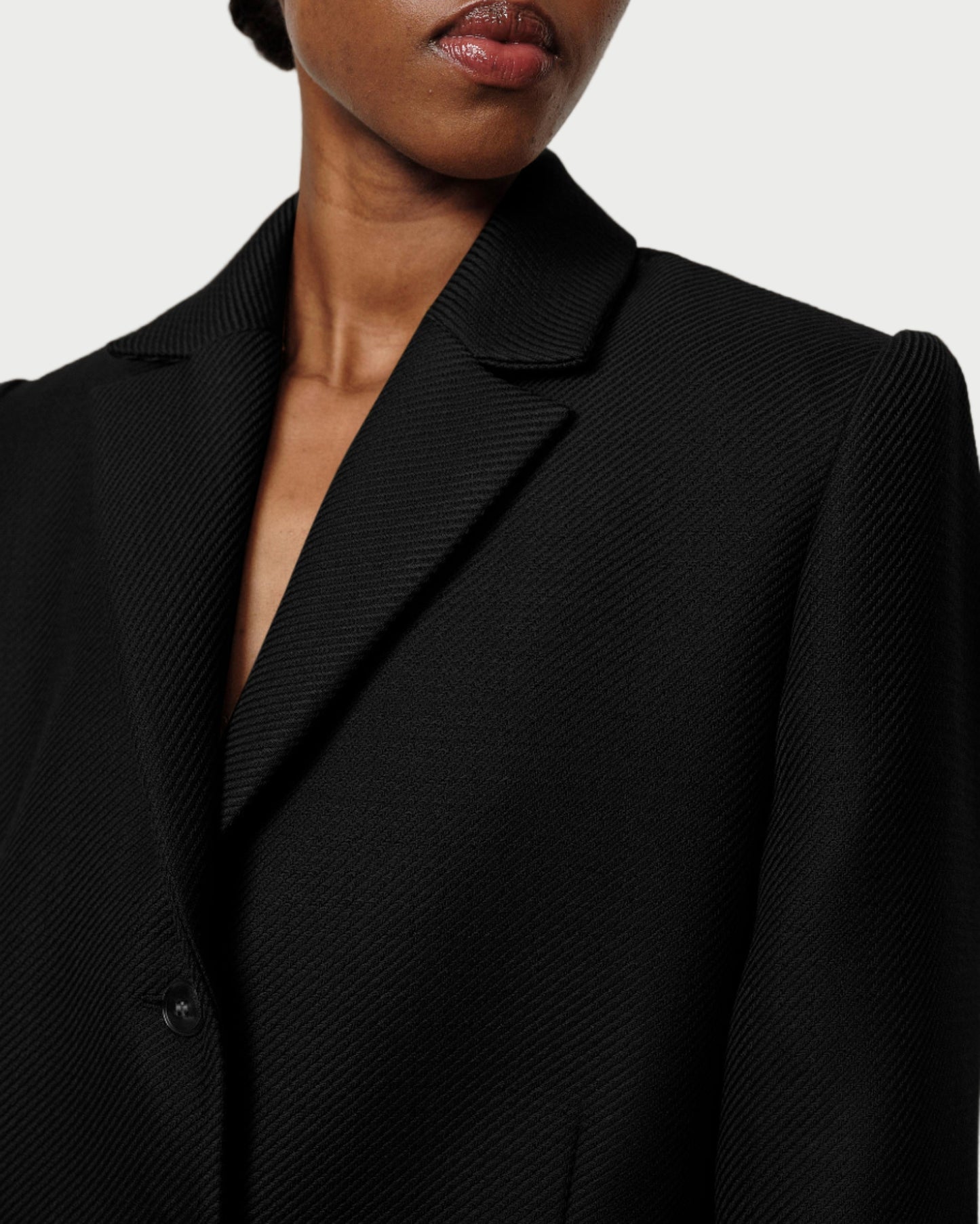 Close-up of a person wearing a black blazer against a neutral background