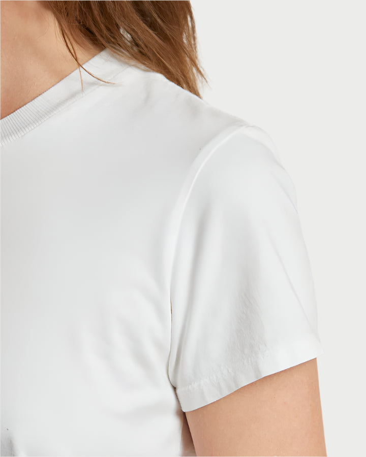 Close-up of a person in a Springsteen Baby Tee by perfectwhitetee. The focus is on the shoulder and upper arm, with visible brown hair. Made from soft Supima cotton, it offers comfort and style against a simple, light backdrop for a minimalist look.