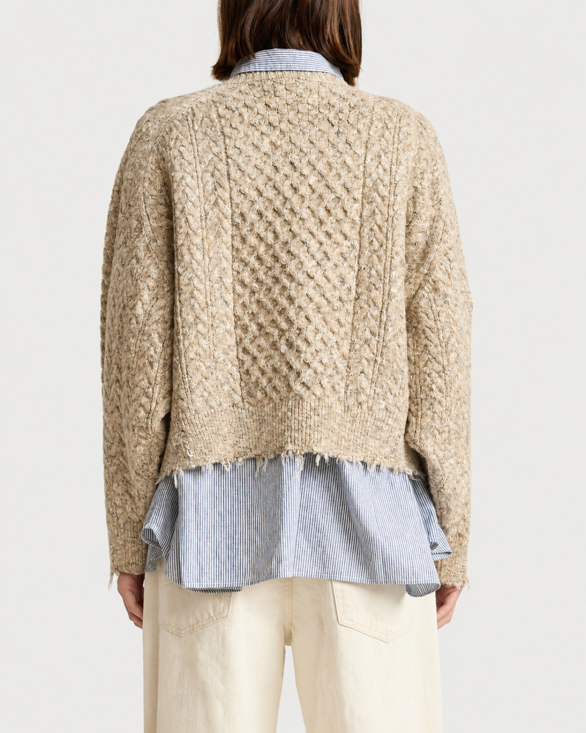Back view of a beige boxy Denimist Oversized Cropped Sweater layered over a blue and white striped collared shirt.