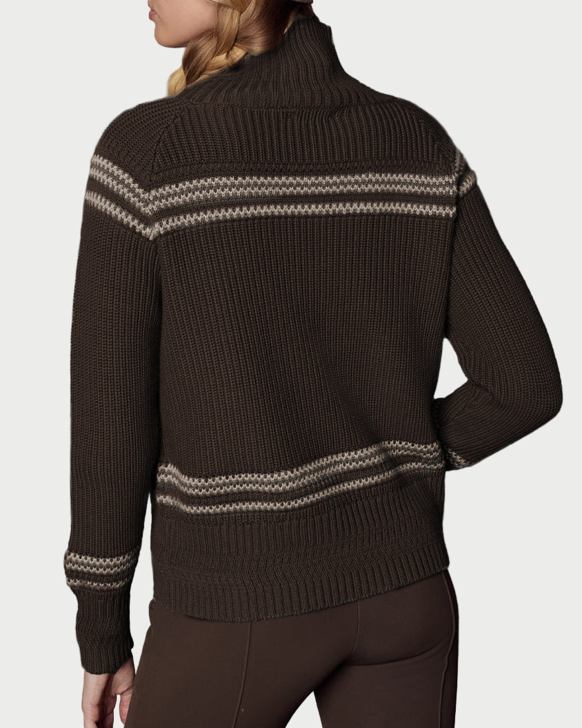 Person wearing a brown sweater with white patterns and matching brown beanie against a gray background
