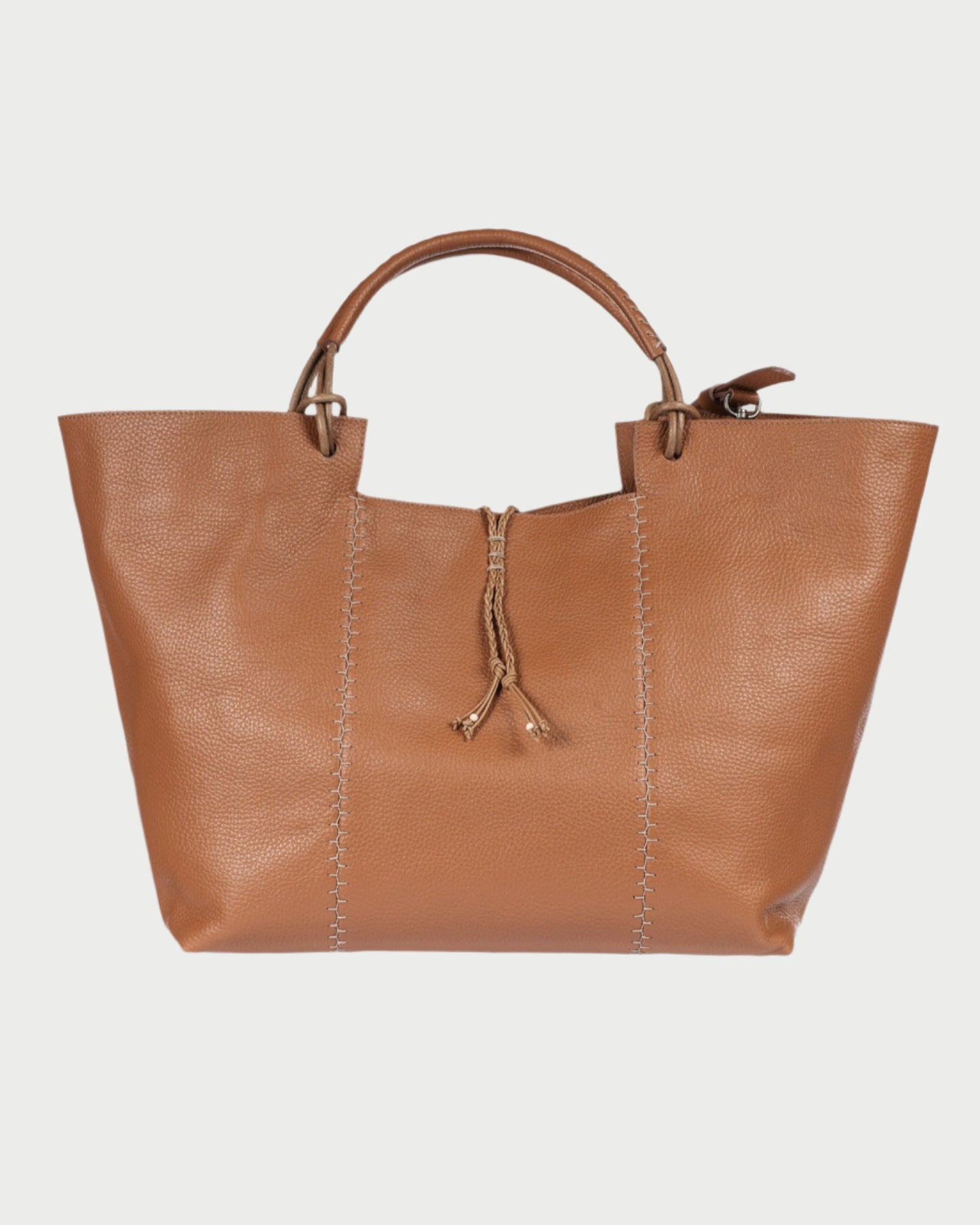 The Large Muflone Tote Bag by Henry Beguelin is a handmade, minimalist brown calfskin leather bag with two handles, prominent stitching along the sides, and a central drawstring closure. Made in Italy and set against a plain white background.