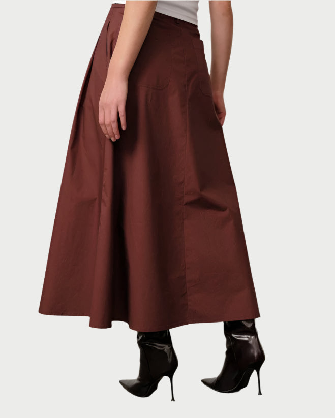 Person wearing a brown skirt and black high-heeled shoes on a plain background