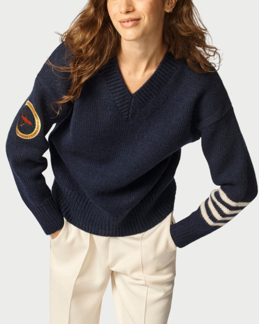 Woman wearing a navy sweater with a patch on a plain background