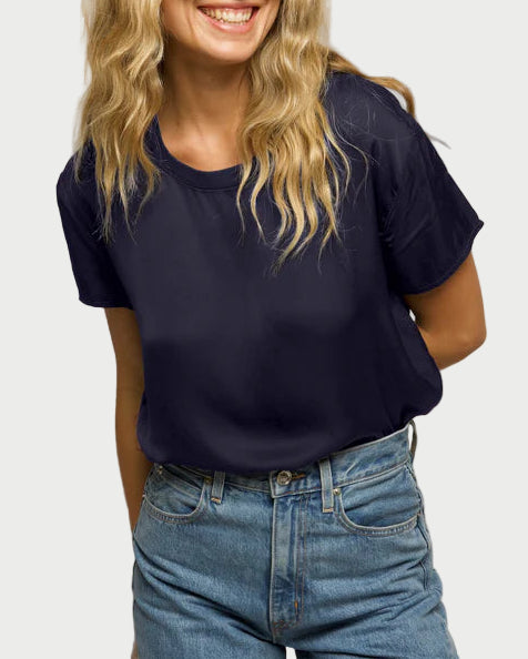 Woman wearing a navy blue t-shirt and blue jeans against a plain background