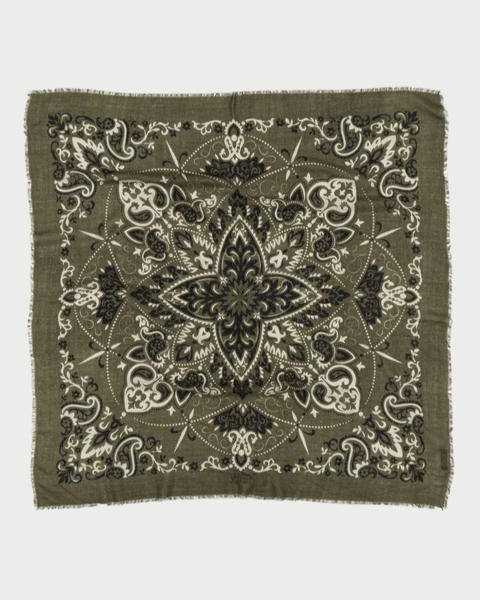 The Bandana Scarf Khaki by Maison Lecomte Flament is a square cotton voile bandana with a fringed edge, featuring a symmetrical paisley and floral design in black, white, and olive green.