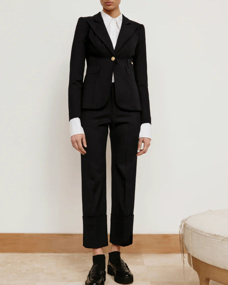 Person wearing a black suit with white shirt and black shoes on a plain background