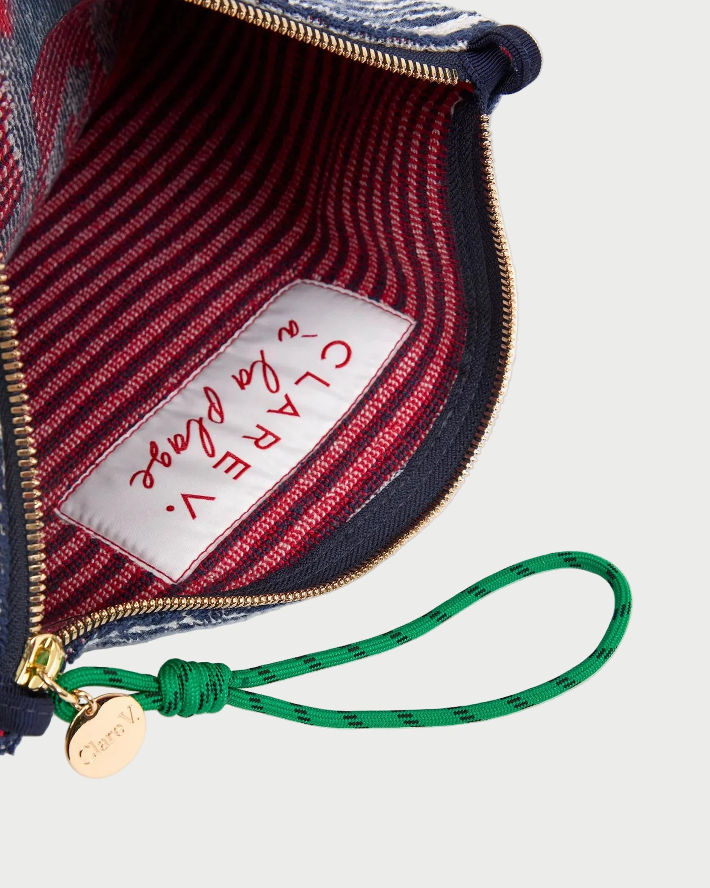 Close-up of a handbag with a visible brand label and green strap.