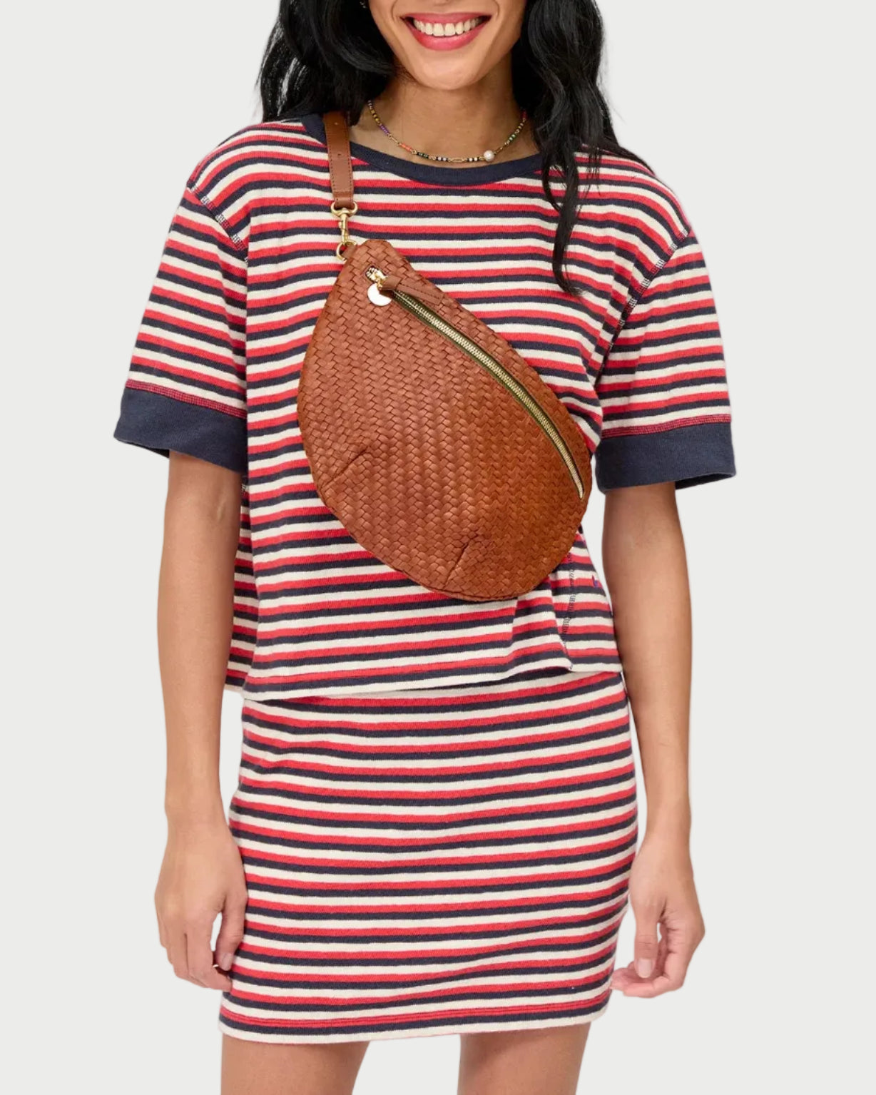 Woman wearing a striped dress with a brown bag on a white background