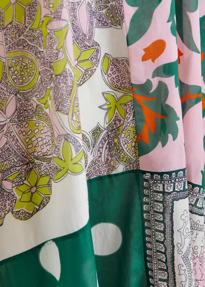 The Hansas Printed Caftan by Essentiel Antwerp features vibrant overlapping fabrics in green, pink, orange, and white with floral and geometric motifs, showcasing bold placed prints and detailed patterns.