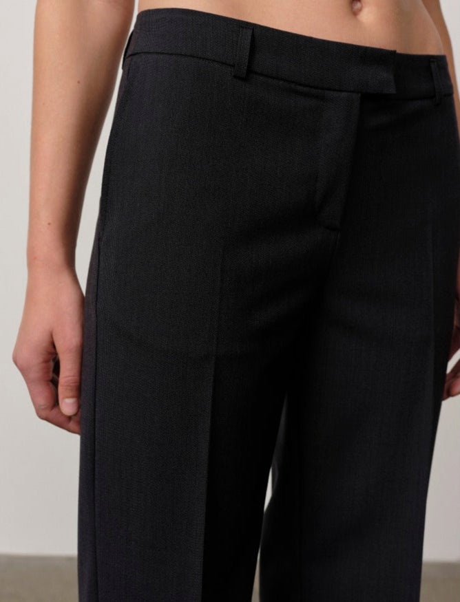 Black pants worn by a person on a plain background