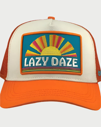 The Soulbyrd Lazy Daze Trucker Hat features orange and white foam mesh, a vibrant chenille sun patch, and bold "LAZY DAZE" lettering on a bright turquoise background.