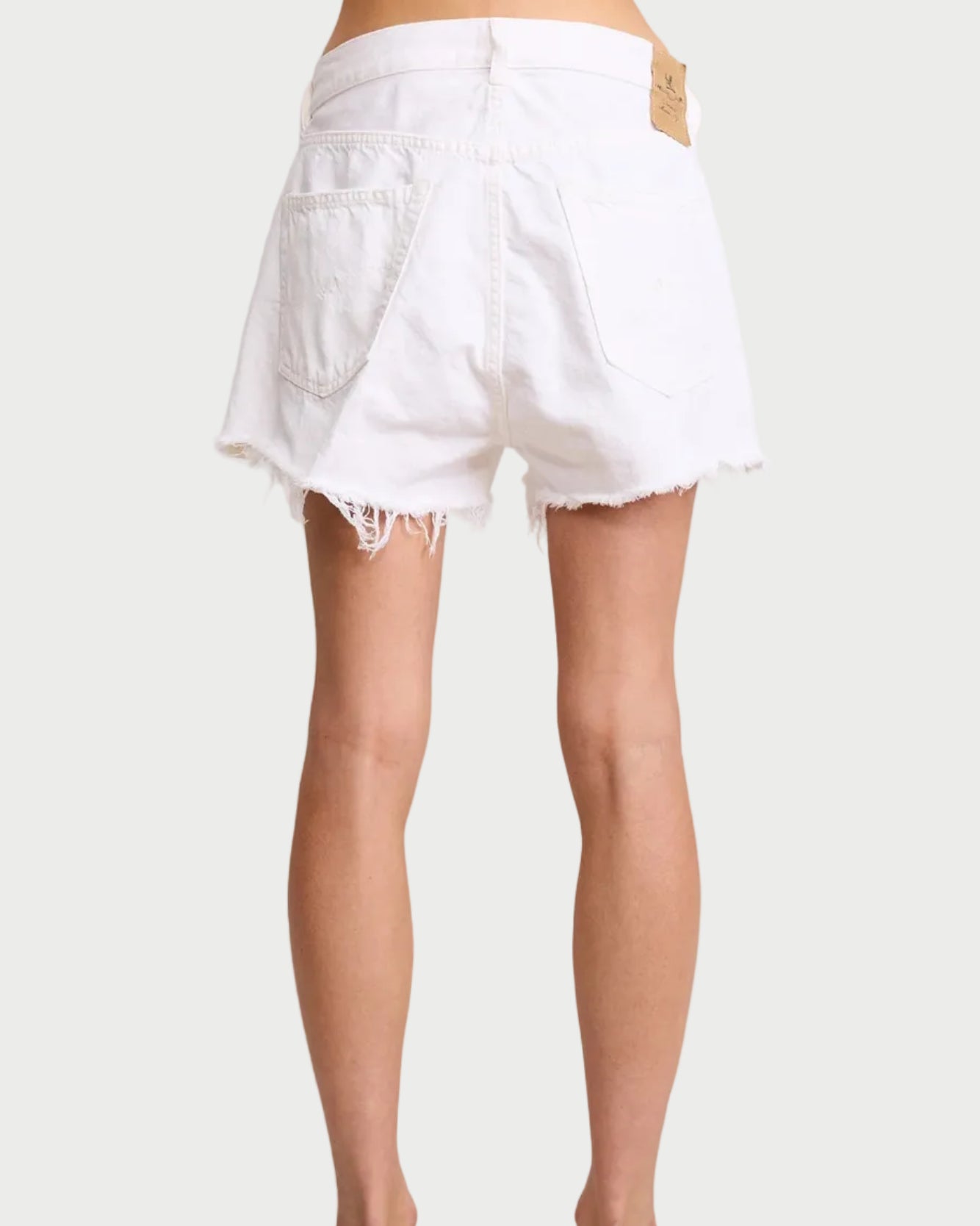White denim shorts worn by a person on a plain background