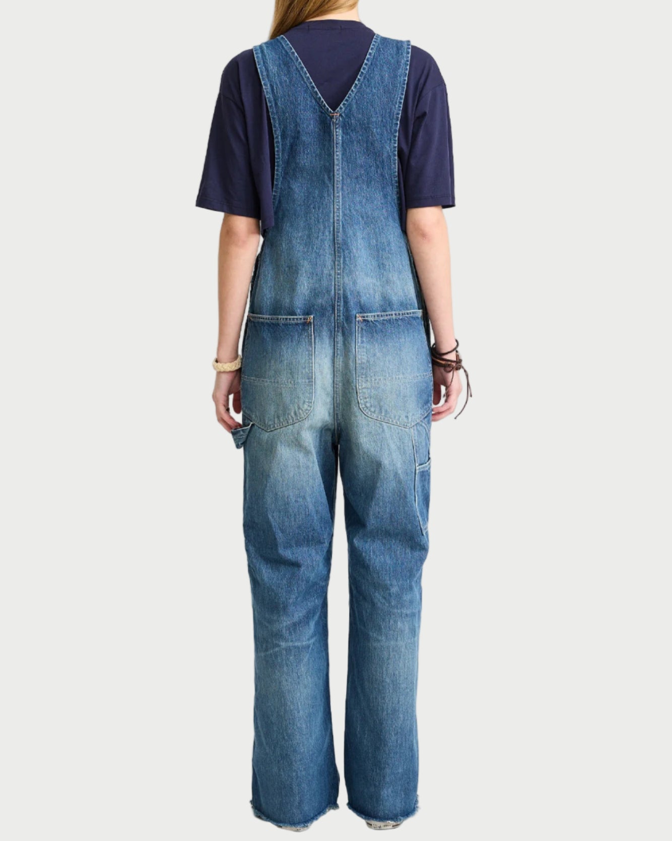 Person wearing blue denim overalls on a white background
