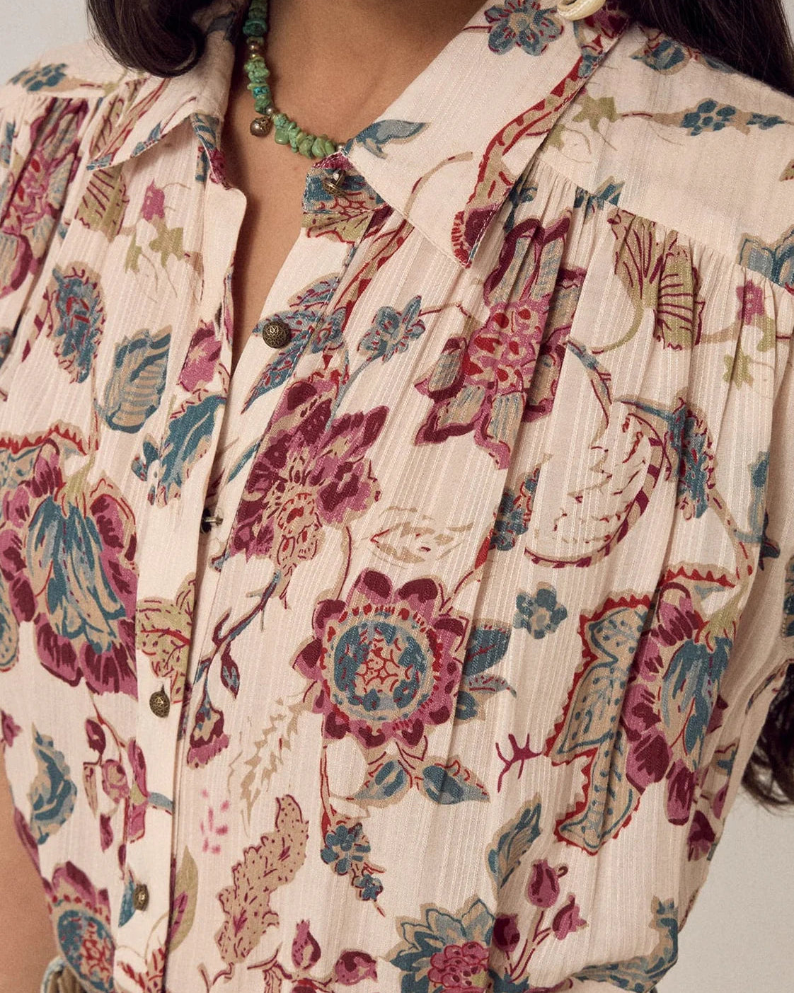 Close-up of a person wearing a floral patterned blouse with a neutral background