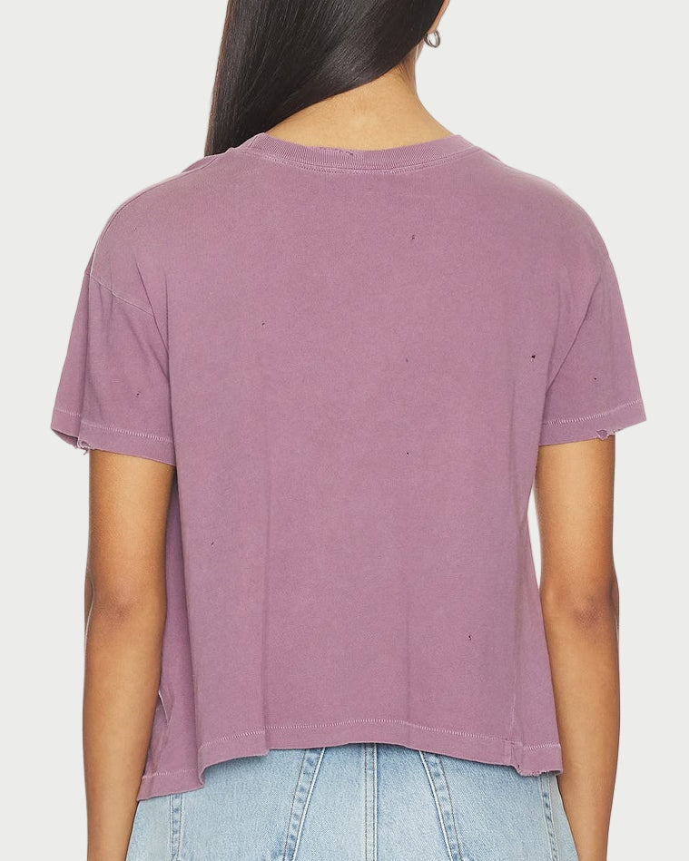 Person wearing a purple t-shirt and denim shorts on a white background