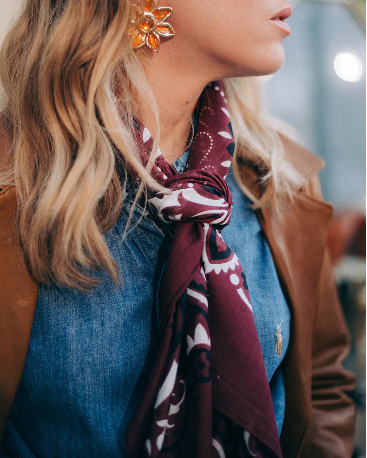 Woman wearing a patterned scarf and floral earrings indoors