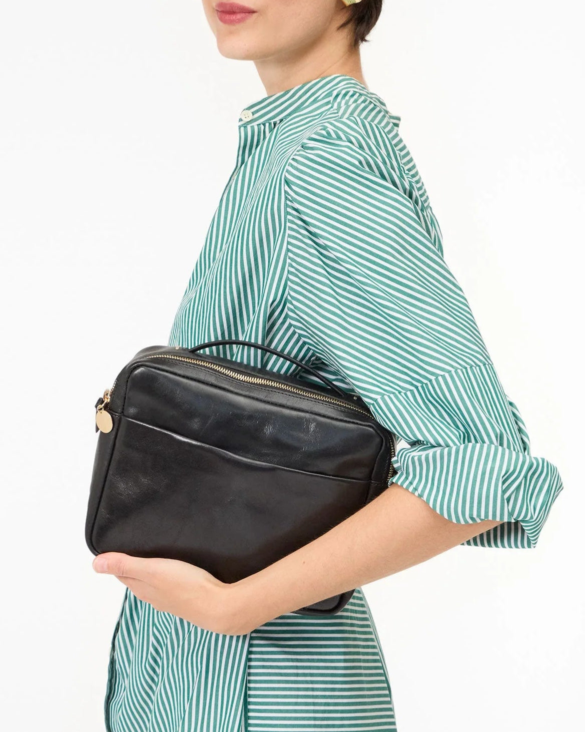 Woman holding a black leather clutch bag against a white background