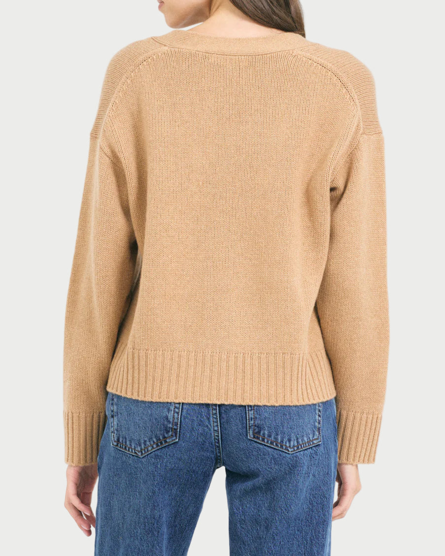 Woman wearing a beige sweater and blue jeans on a white background