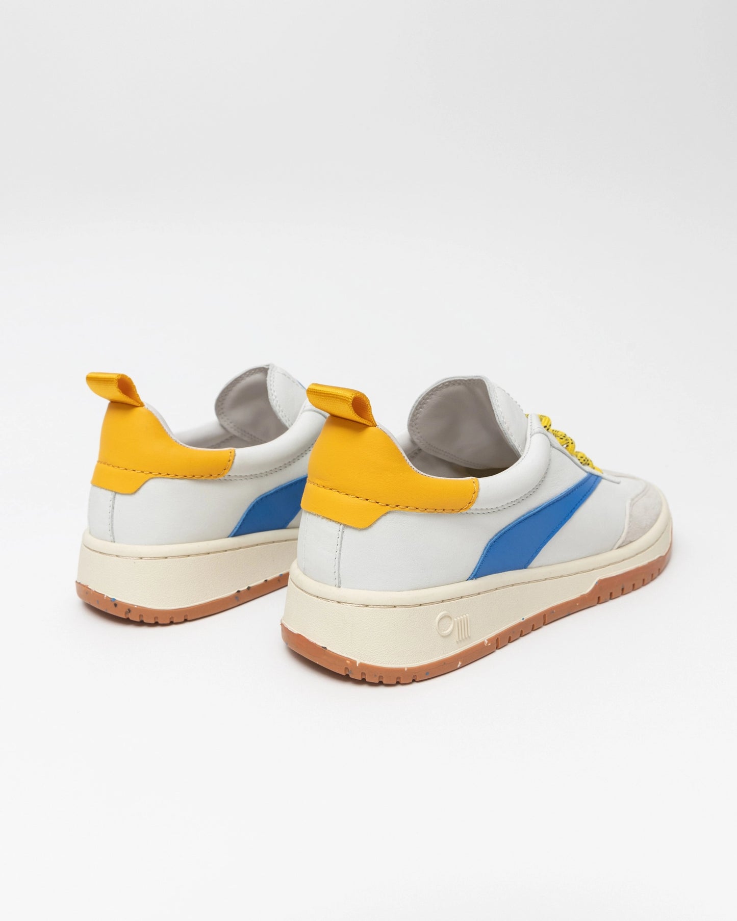 A pair of Oncept's Panama Sneaker, boasting a stylish and comfortable design with white, blue, and yellow accents and a tan sole. The sneakers are equipped with a back loop and set against a plain white background.