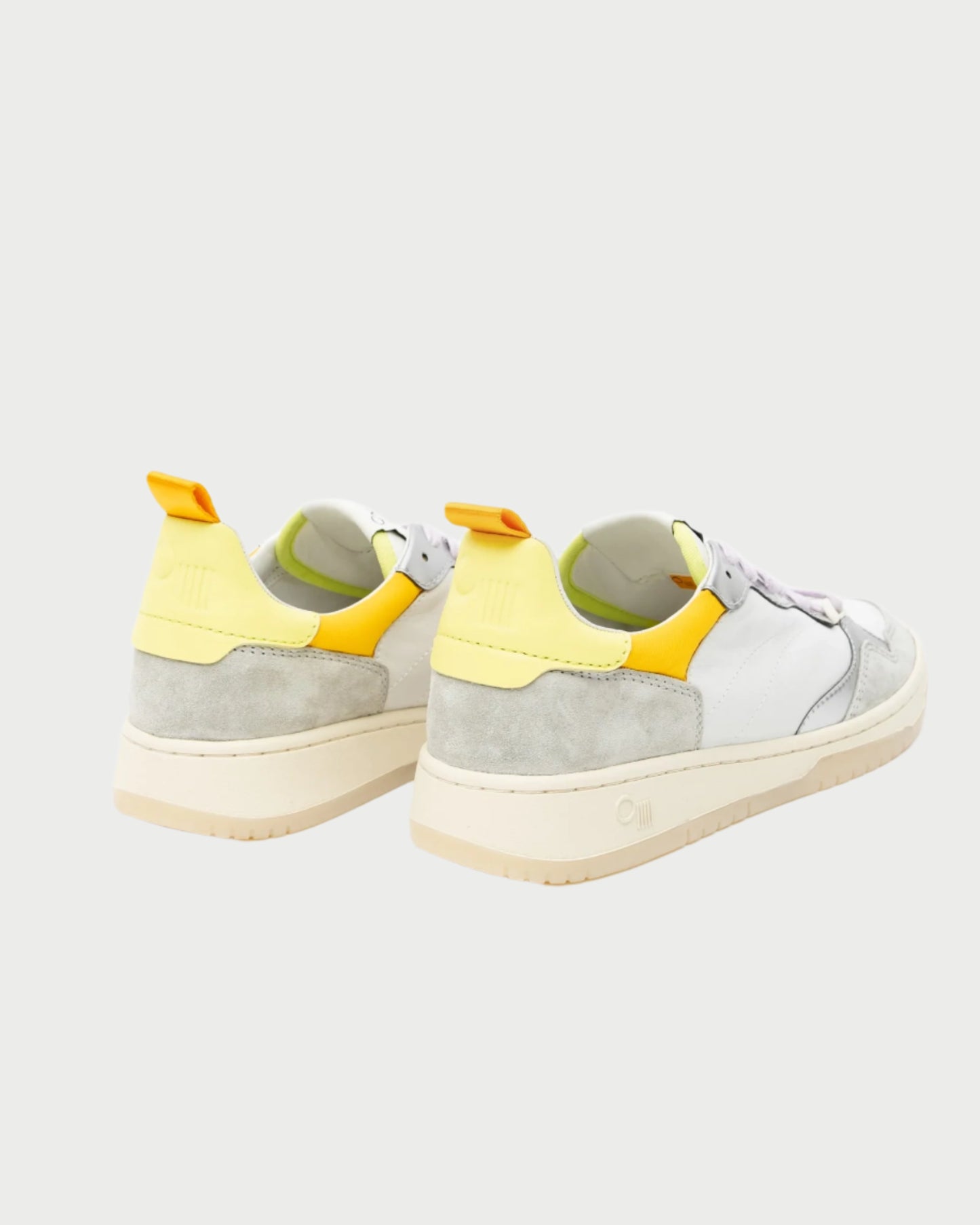 The Oncept Phoenix Sneaker features a chic retro design with a beige sole. It showcases a white and light gray color scheme, highlighted by striking yellow accents on the heel and collar for added flair. Designed with comfort in mind, these minimalistic sneakers are set against a plain light backdrop.