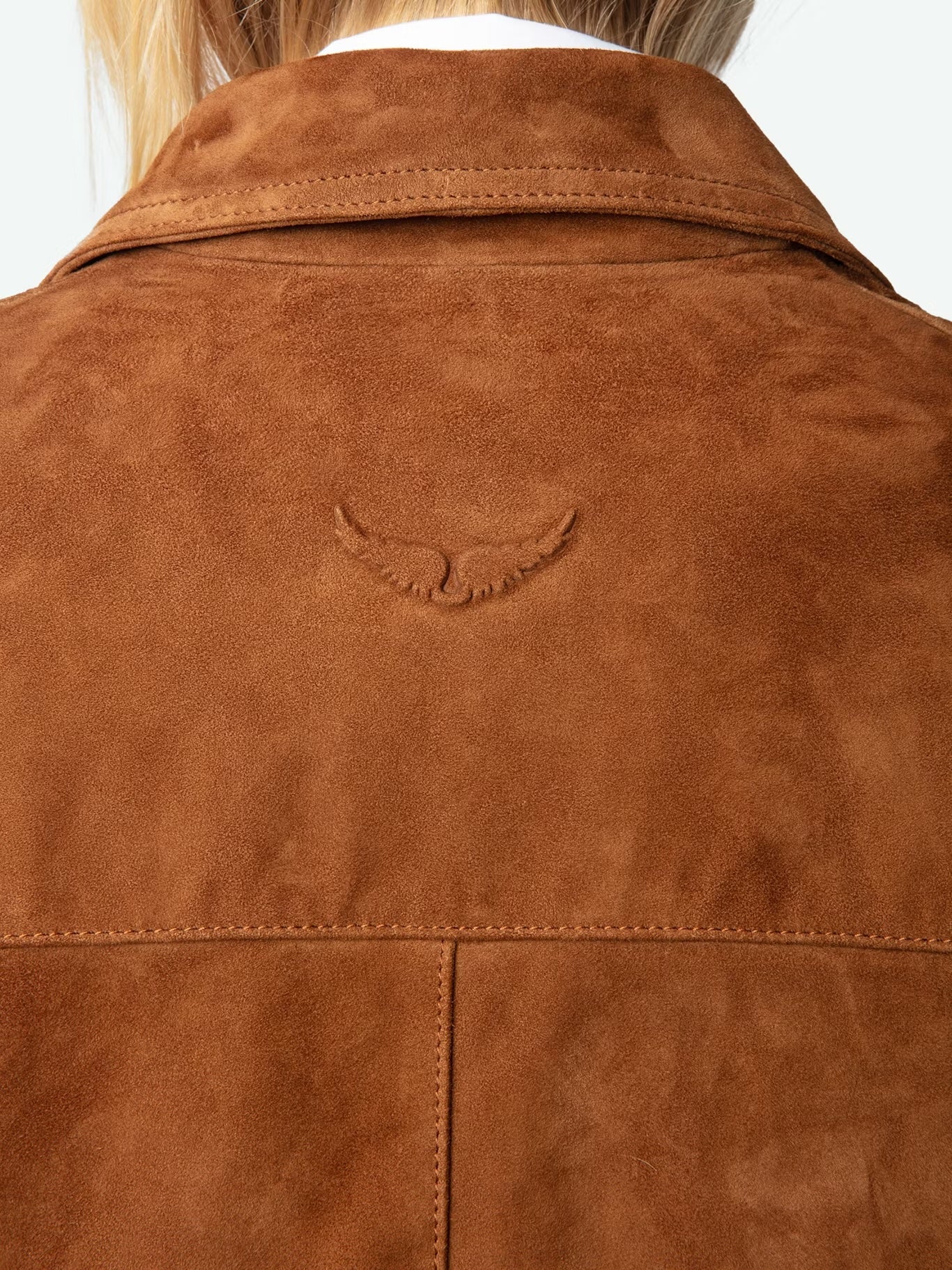 Close-up of a brown suede jacket with a brand logo on a white background