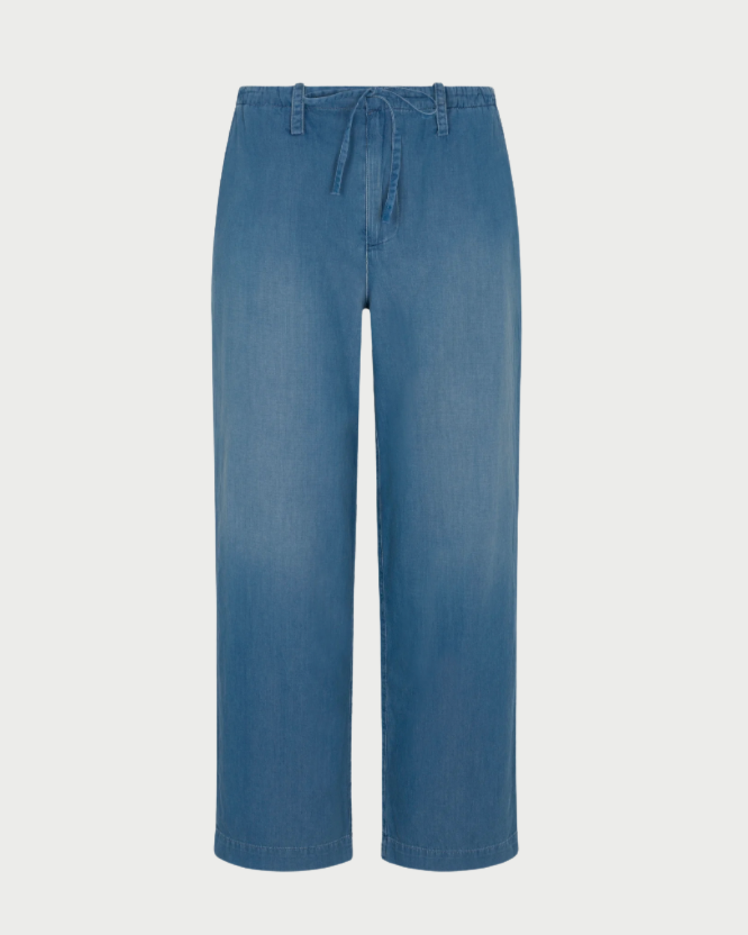 The SPRWMN Helena Drawstring Pants feature light blue chambray cotton, a relaxed straight-leg fit, elastic waistband with drawstring tie, and belt loops, displayed on a white background.