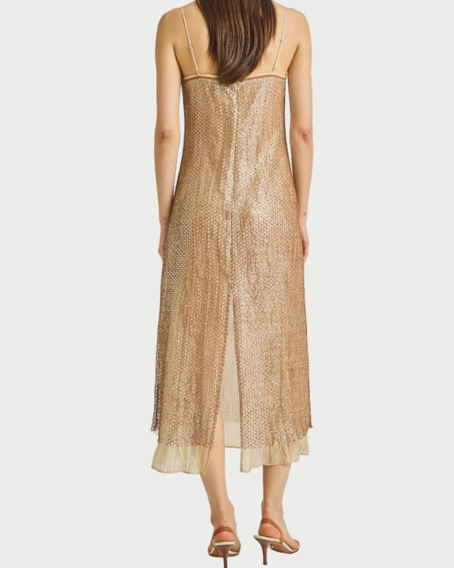 Woman wearing a gold sequin dress on a plain background