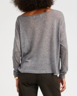 Person wearing a gray sweater and black pants on a white background