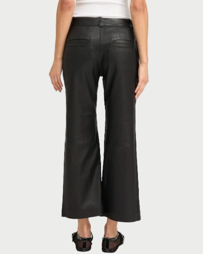 A person shown from the back wears SPRWMN Cropped Leather Trousers in black French lambskin, paired with a white sleeveless top and black shoes.