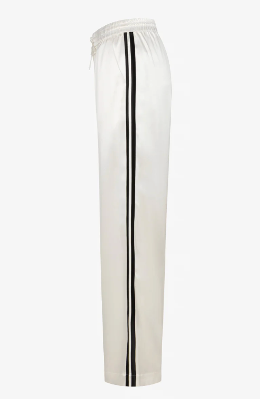 Side view of SPRWMN Baggy Athletic Pant in white satin, featuring a wide-leg fit, elastic waistband, and two black vertical stripes down each leg. Brand: SPRWMN.