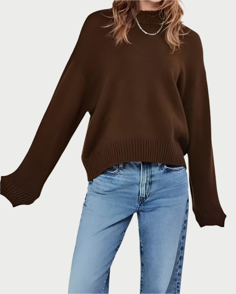 Wearing the Frame Oversized Cashmere Crew Sweater in brown with light blue jeans radiates pure comfort as the loose-fitting sweater and its long sleeves drape gracefully against a plain, light-colored background.