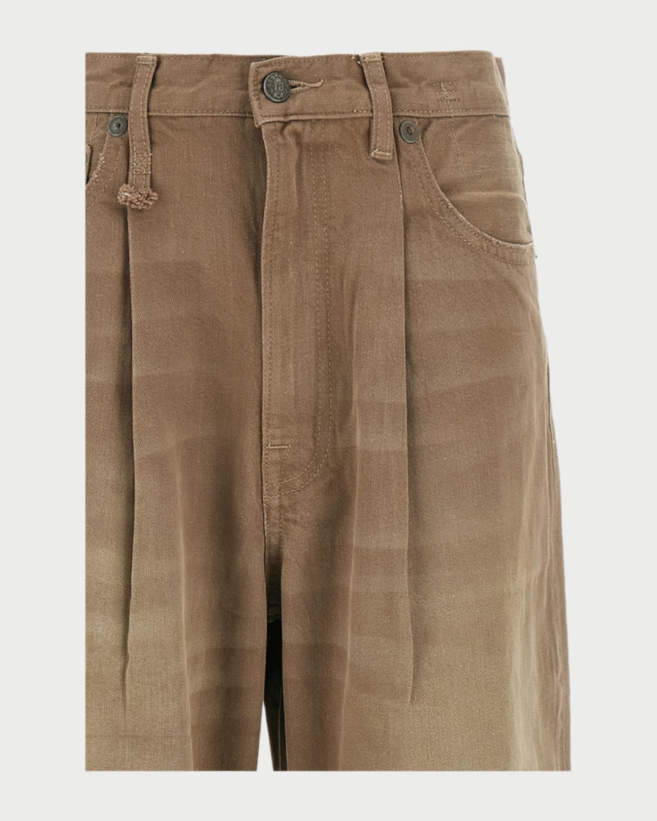 Close-up of R13 Damon Pleated Jeans in Sawdust: brown, wide-leg denim with pleats, button and zip closure, belt loops, and front pockets. The oversized fit highlights subtle shading and textured khaki fabric.
