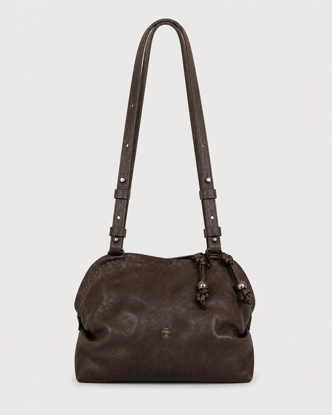 The Henry Beguelin Leather Bolla Bassa Bag is a dark brown Italian leather shoulder bag featuring adjustable double straps with decorative knots and a subtle embossed Henry Beguelin logo on the front. Handcrafted with a simple, slightly gathered design, it is showcased against a plain white background.