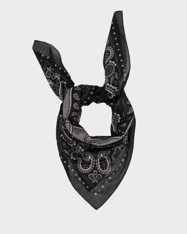 The Rodeo Scarf by Maison Lecomte Flament is a black cotton voile bandana with a classic white and gray pattern, worn knotted with pointed tips up and a triangular end down.