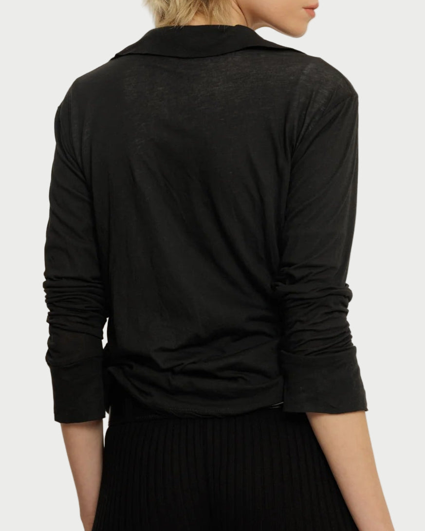 Person wearing a black long-sleeve top and black pants against a plain background