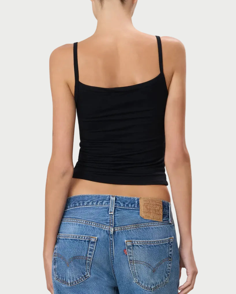 Person wearing a black tank top and blue jeans on a light gray background