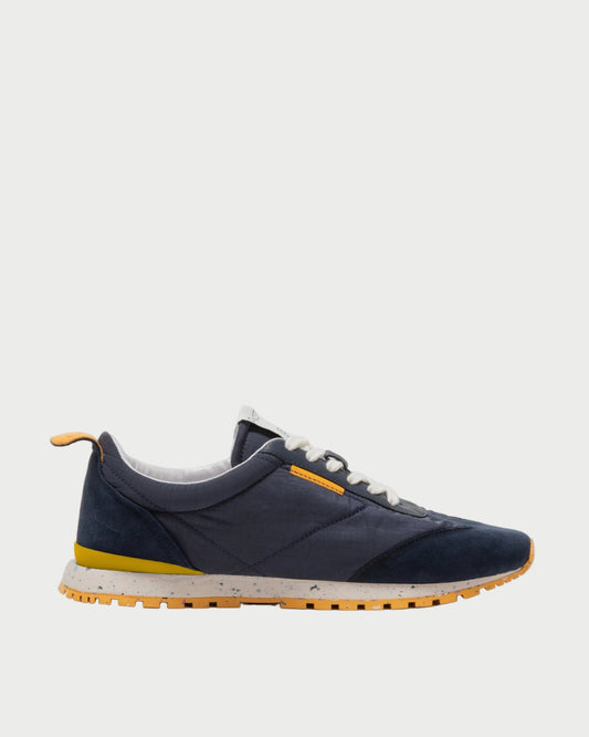 Navy blue sneaker with yellow sole on a light gray background